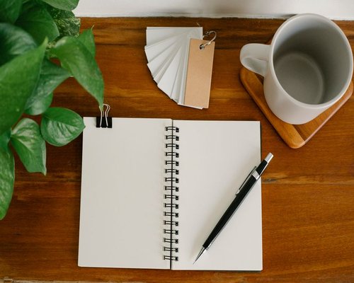 Coffee cup and notebook on a wooden desk
